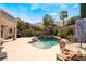 Backyard with beautiful in-ground pool with rock features and lush landscaping and table with umbrella at 11285 Fiesole St, Las Vegas, NV 89141
