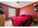 Comfortable bedroom with red walls, plush bedding, and a ceiling fan for a cozy ambiance at 11285 Fiesole St, Las Vegas, NV 89141