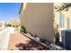 Exterior backyard showcases a retaining wall and the side of a two story home with an AC unit at 1185 Via Dimartini, Henderson, NV 89052