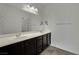 Bathroom with a double sink vanity featuring dark wood cabinets, and a large mirror that reflects the well-lit space at 1185 Via Dimartini, Henderson, NV 89052