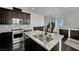 Elegant kitchen featuring dark wood cabinets, granite countertops, stainless appliances, and a center island with sink at 1185 Via Dimartini, Henderson, NV 89052
