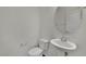 Neat powder room features pedestal sink, round mirror, and toilet, all complemented by neutral wall color at 1185 Via Dimartini, Henderson, NV 89052