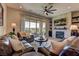 Comfortable living room features a stone fireplace, a ceiling fan, and access to the outdoor patio at 12318 Tudor Arch Dr, Las Vegas, NV 89138