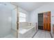 Bright bathroom featuring a frosted glass shower, soaking tub, and tile flooring at 1924 Coralino Dr, Henderson, NV 89074