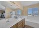 Bright primary bathroom featuring double sinks, lots of counter space, a separate shower, and a luxurious soaking tub under a window at 2147 Bridle Wreath Ln, Las Vegas, NV 89156