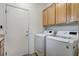 Well-lit laundry room featuring a side-by-side washer and dryer, and ample upper cabinet space at 2804 Sapphire Desert Dr, Henderson, NV 89052
