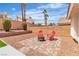 Backyard showcasing a gravel area with a paved patio, adorned with a fire pit and red chairs, perfect for relaxing at 3109 Siena Cir, Las Vegas, NV 89128