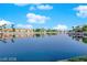 A serene lake view features beautiful waterfront homes and calm waters, reflecting blue skies and fluffy clouds at 3109 Siena Cir, Las Vegas, NV 89128