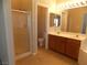 Bathroom with double sinks, warm wood cabinets, stand up shower with glass doors, and beige tile at 319 Mulberry Glen Dr, North Las Vegas, NV 89031