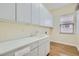 Bright laundry room with sink, white cabinets, and wood-look flooring at 3805 Specula Wing Dr, North Las Vegas, NV 89084