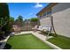 Turf backyard area with a porch swing, seating, landscaping, and a serene outdoor setting at 4208 Agosta Luna Pl, Las Vegas, NV 89135