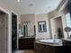 Bathroom featuring a large soaking tub with marble surround, dual sinks and etched mirrors at 4208 Agosta Luna Pl, Las Vegas, NV 89135