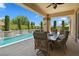 Covered patio with elegant outdoor dining area, overlooking a pool and lush landscaping, creating an ideal space at 4208 Agosta Luna Pl, Las Vegas, NV 89135