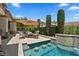 Backyard swimming pool featuring a seating area with umbrella and a soothing waterfall feature for a tranquil oasis at 4208 Agosta Luna Pl, Las Vegas, NV 89135