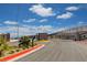 View of community entrance road with desert landscaping, decorative block wall, and black metal fencing at 5236 Sunstone Mesa Dr, Las Vegas, NV 89166