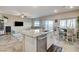 Open kitchen with stainless appliances and granite island connected to living and dining area with ample natural light at 5236 Sunstone Mesa Dr, Las Vegas, NV 89166