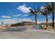 Street view featuring the community sign, lush palm trees, and a well-maintained circular median at 5236 Sunstone Mesa Dr, Las Vegas, NV 89166