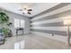 Bright bedroom with white tile floors, a ceiling fan, and horizontal gray-and-white striped accent wall at 6971 Moaning Cavern St, Las Vegas, NV 89131