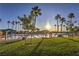 A picturesque community lake featuring a sandy beach, lounging areas, and tall palm trees under a clear blue sky at 7641 Sea Wind Dr, Las Vegas, NV 89128