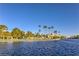 Scenic lake view with palm trees, sandy beach, lakeside lounging spots, and the community center set against a blue sky at 7641 Sea Wind Dr, Las Vegas, NV 89128