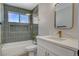 Modern bathroom with gray tiled walls, white vanity, and gold fixtures at 7805 Leavorite Dr, Las Vegas, NV 89128