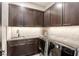 Contemporary laundry room featuring dark cabinetry, mosaic backsplash, sink, and modern washer and dryer at 787 Keyland St, Las Vegas, NV 89138