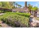 Welcoming stone community sign surrounded by lush landscaping and palm trees under a bright blue sky at 9125 Las Manaitas Ave # 302, Las Vegas, NV 89144