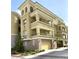 Exterior corner view of a beige three-story condominium with balconies, garage doors, and manicured landscaping at 9125 Las Manaitas Ave # 302, Las Vegas, NV 89144