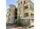 Elegant multi-story condo with a tan stucco finish, private balconies and manicured landscaping around the building at 9125 Las Manaitas Ave # 302, Las Vegas, NV 89144