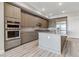 Modern kitchen features stainless steel appliances, wood-grain cabinets, and a large island with countertop seating at 9125 Las Manaitas Ave # 302, Las Vegas, NV 89144