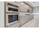 Close-up of the kitchen featuring stainless steel double ovens, wood-grain cabinetry, and white subway tile backsplash at 9125 Las Manaitas Ave # 302, Las Vegas, NV 89144