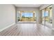 Bright, empty living room with wood-look floors and sliding glass doors to the balcony with a golf course view at 9125 Las Manaitas Ave # 302, Las Vegas, NV 89144