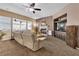 Cozy living room with a fireplace, ceiling fan, and natural light from large windows at 9362 Wilderness Glen Ave, Las Vegas, NV 89178