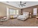 Spacious main bedroom featuring large windows, accent wall, ceiling fan, and neutral carpeting at 9362 Wilderness Glen Ave, Las Vegas, NV 89178
