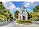 Picturesque neighborhood entrance with clocktower, manicured hedges, and colorful flowers at 9704 Royal Lamb Dr, Las Vegas, NV 89145