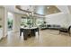 Open-concept living and dining area with modern light fixture and hardwood floors, flowing to the backyard pool and patio at 10277 Roma Madre Ave, Las Vegas, NV 89135