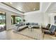 The sunlit living area has a view of the pool and rock waterfall, neutral color palette, and comfortable seating arrangement at 10277 Roma Madre Ave, Las Vegas, NV 89135
