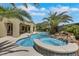 This backyard shows a pool and integrated spa with a rock waterfall feature, set amidst lush tropical landscaping at 10277 Roma Madre Ave, Las Vegas, NV 89135