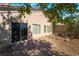 View of the private backyard featuring gravel landscaping, brick patio, mature trees, and a sliding glass door at 10458 Gabaldon St, Las Vegas, NV 89141