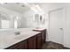 A well-lit bathroom with double sinks, dark wood cabinets, and tile flooring at 10458 Gabaldon St, Las Vegas, NV 89141