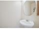 Clean half bathroom with pedestal sink, round mirror and neutral colors at 10948 Carberry Hill St, Las Vegas, NV 89141