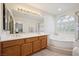 Bright bathroom featuring double sinks, large mirror, soaking tub, and separate shower at 10948 Carberry Hill St, Las Vegas, NV 89141