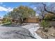 Property featuring desert landscaping, a circular driveway, and mature trees, enhancing its natural setting at 11177 Twilight Times Ct, Las Vegas, NV 89135