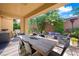 Inviting covered patio with a large dining table, fire pit, and lush landscaping at 11340 Espadrille Ct, Las Vegas, NV 89138