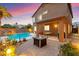 Outdoor living space with a covered patio, dining set, fire pit, and a sparkling pool for relaxing and entertaining at 1200 Dream Bridge Dr, Las Vegas, NV 89144
