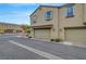 Two-car garage on a neutral-toned townhome featuring tile roof, shutters, and landscaping at a street corner at 1200 Paradise Basin Ct, Henderson, NV 89002