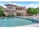 The beautiful two-story home has a backyard pool, balcony, neutral exterior, and lush trees at 1972 Alcova Ridge Dr, Las Vegas, NV 89135