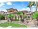 A beautiful two-story home boasts desert landscaping, a neutral exterior, and several palm trees at 1972 Alcova Ridge Dr, Las Vegas, NV 89135