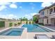 A sparkling pool and spa are surrounded by desert landscaping and a beige house under a blue sky at 1972 Alcova Ridge Dr, Las Vegas, NV 89135