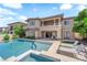 A luxurious pool and spa are surrounded by patio and lawn seating, along with a beige two-story house at 1972 Alcova Ridge Dr, Las Vegas, NV 89135